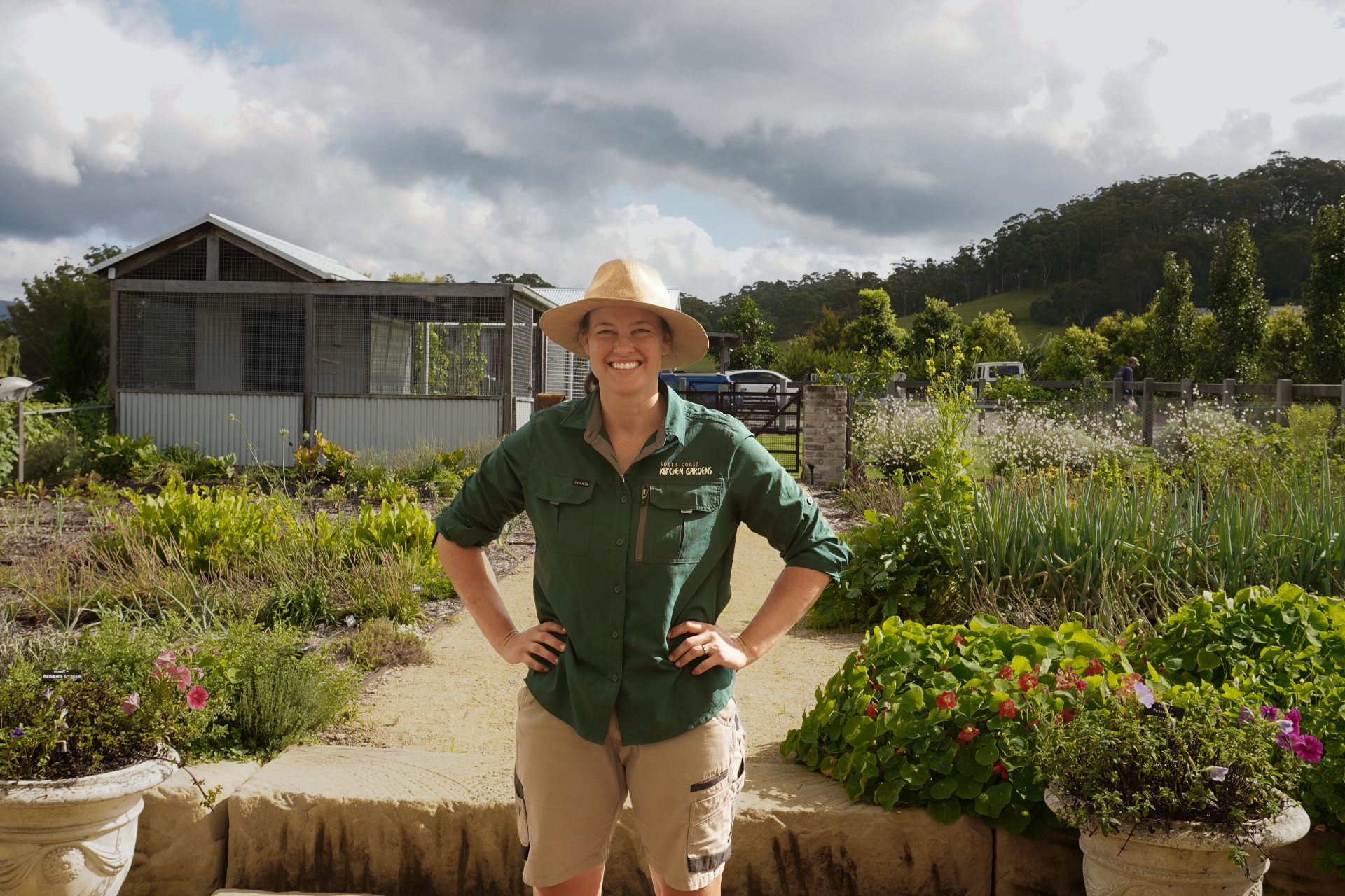 Friendly kitchen garden consultant smiling while tending to leafy greens